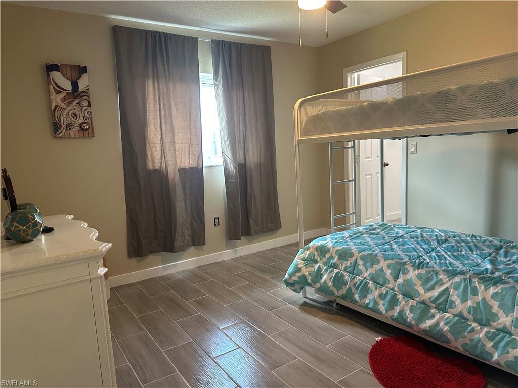 Image 2: Room featuring wood-finish tile flooring, a window with drapery, light tan wall color, and a ceiling fan