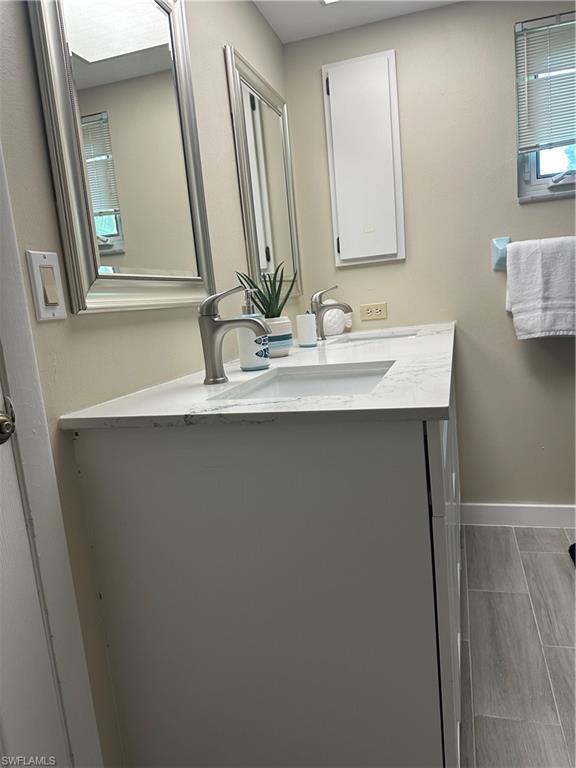 Image 4: Dual vanity with integrated sinks and satin nickel faucets, framed mirrors, recessed medicine cabinet, and wood-finish tile flooring