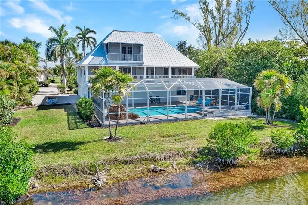 Image 1: Two-story waterfront residence featuring a screened-in pool and an upper-level balcony