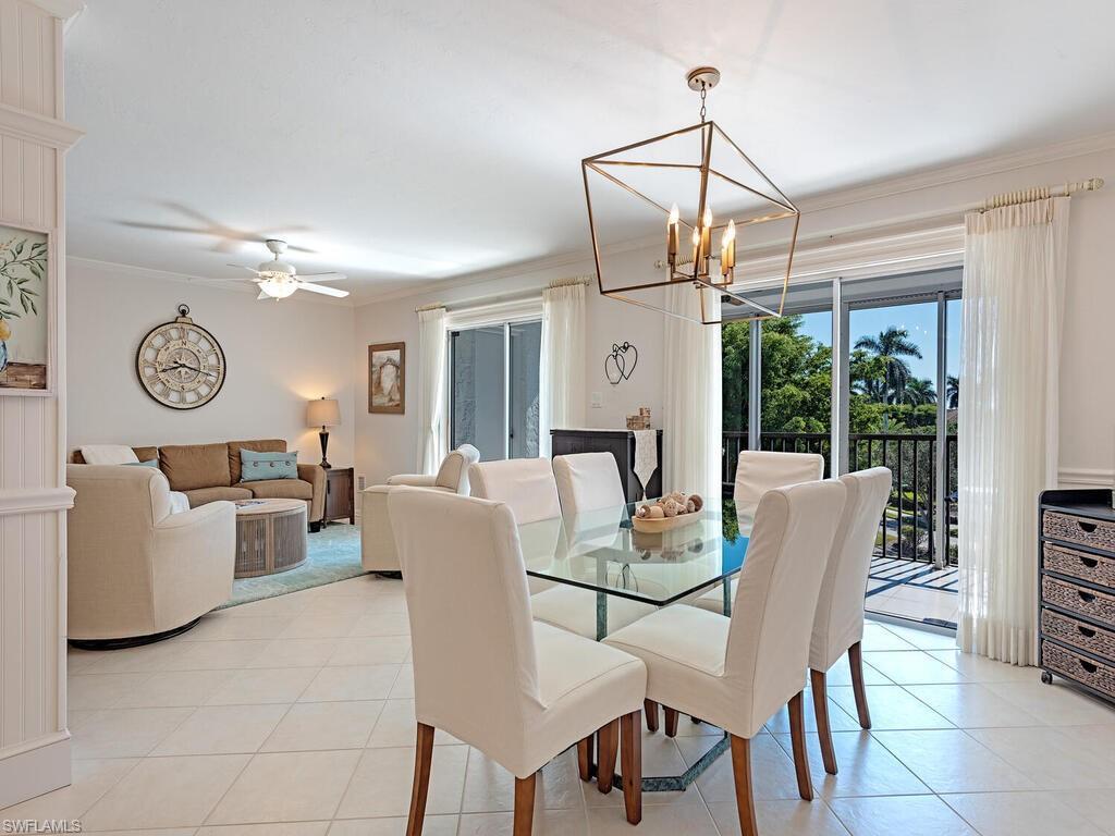 Image 2: Dining area with light tile patterned floors, crown molding, ceiling fan, and a chandelier