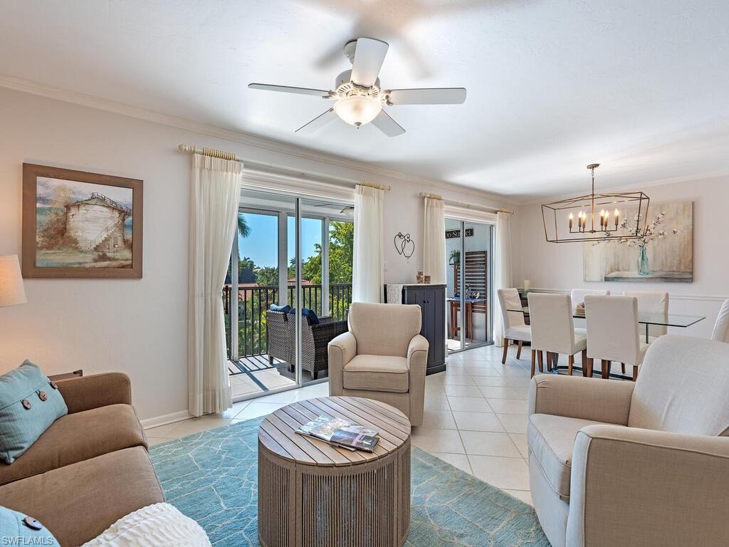 Image 3: Tiled living area with ornamental molding, a chandelier, and ceiling fan
