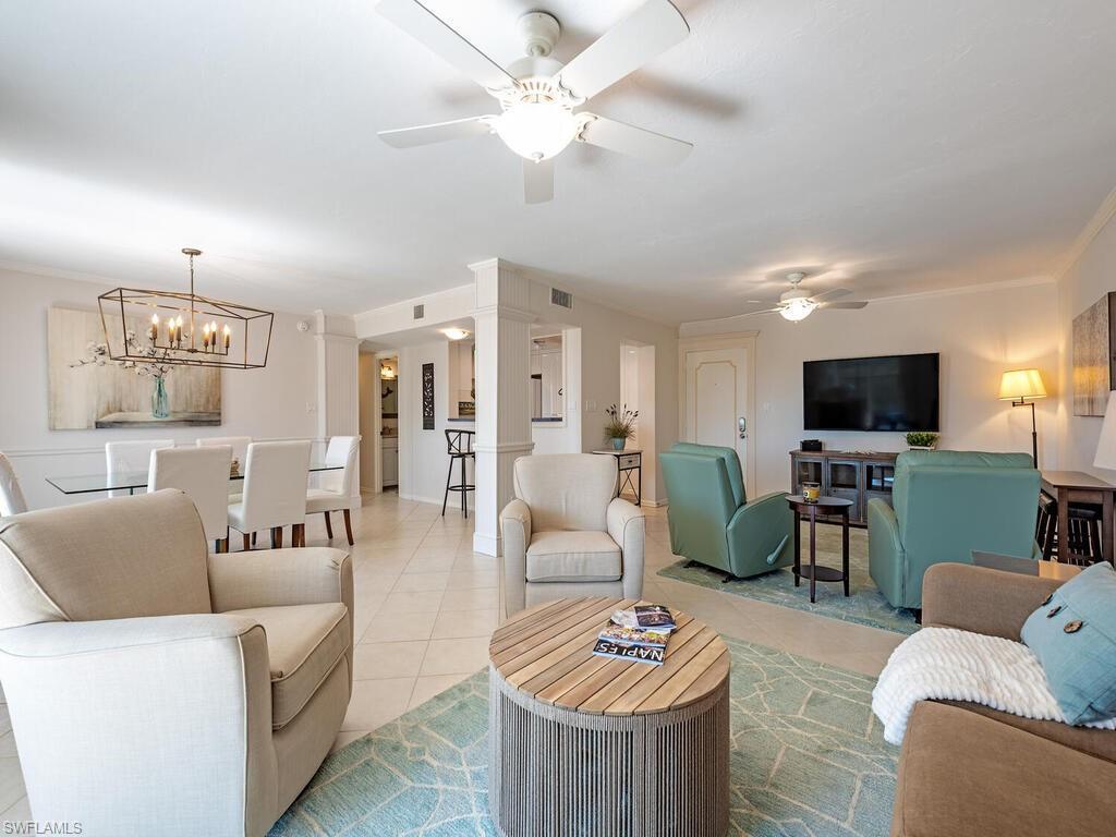 Image 4: Living area with light tile patterned floors, a ceiling fan, and a chandelier