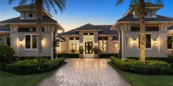 Image 3: View of front facade featuring stucco siding, a lawn, decorative driveway, and french doors