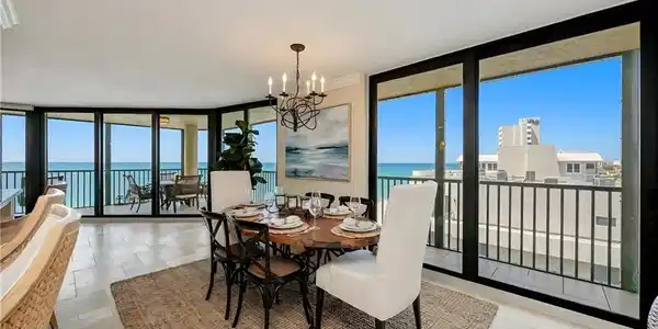 Image 4: Dining area with expansive windows, a chandelier, a water view, and light stone finish floors