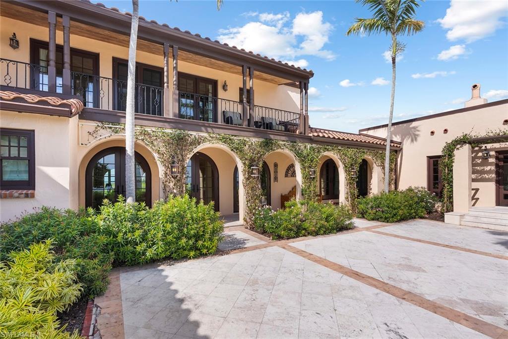 Image 4: MAIN HOUSE - The property features an exterior with arched doorways and windows, tile roofing, and a second-story balcony with dark railings