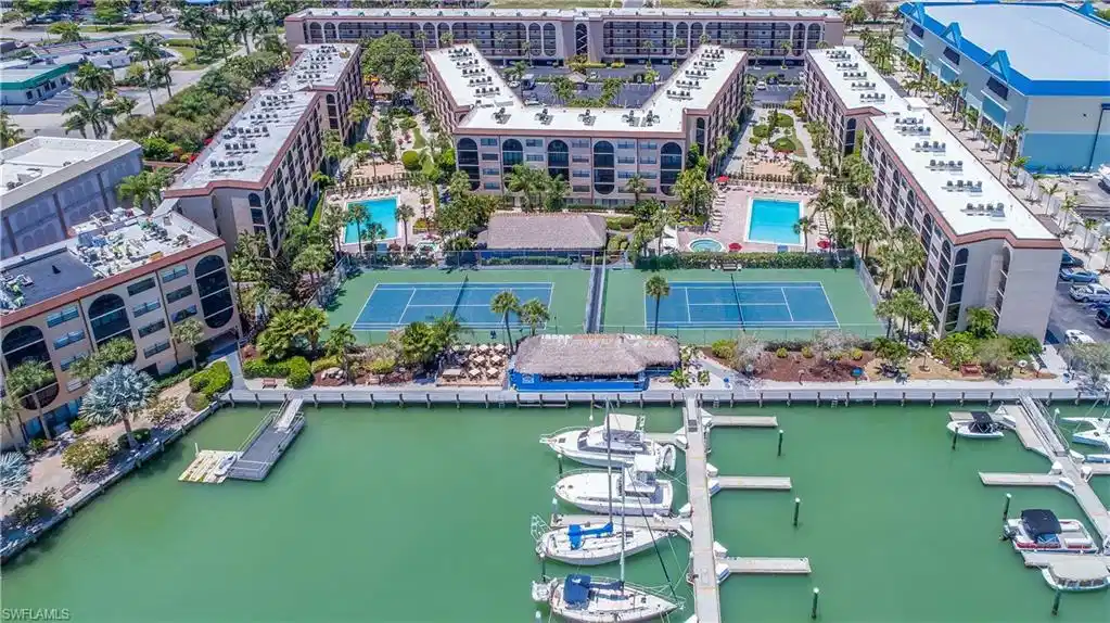 Image 1: Waterfront condominium complex featuring a private marina with multiple boat slips, two outdoor swimming pools, and two tennis courts