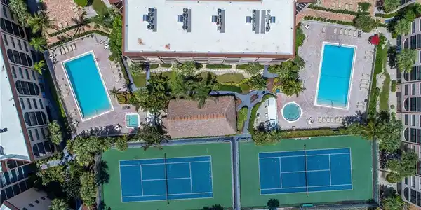 Image 2: Expansive outdoor recreational area featuring two tennis courts, two swimming pools, and a spa, surrounded by lush landscaping and mature palm trees