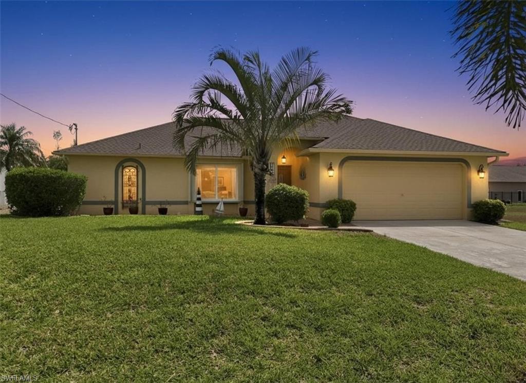 Image 1: View of front of home with stucco siding, a garage, a front yard, and concrete driveway
