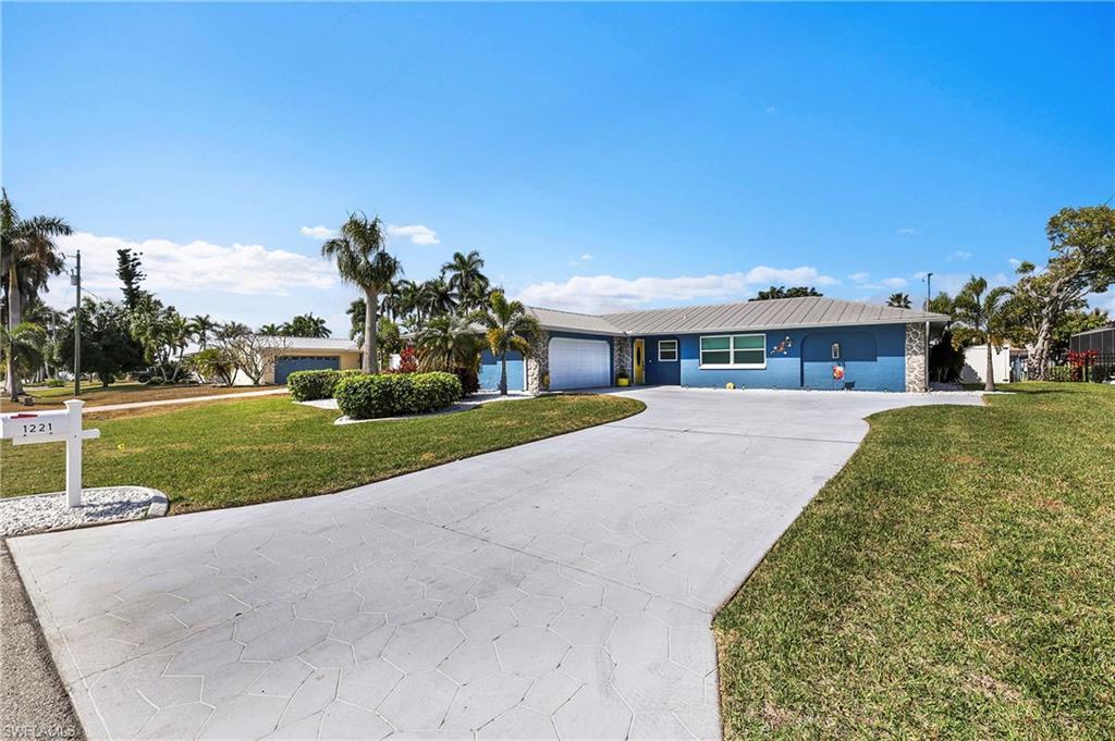 Image 2: Single-story residence featuring a blue exterior with stone accents and a metal roof