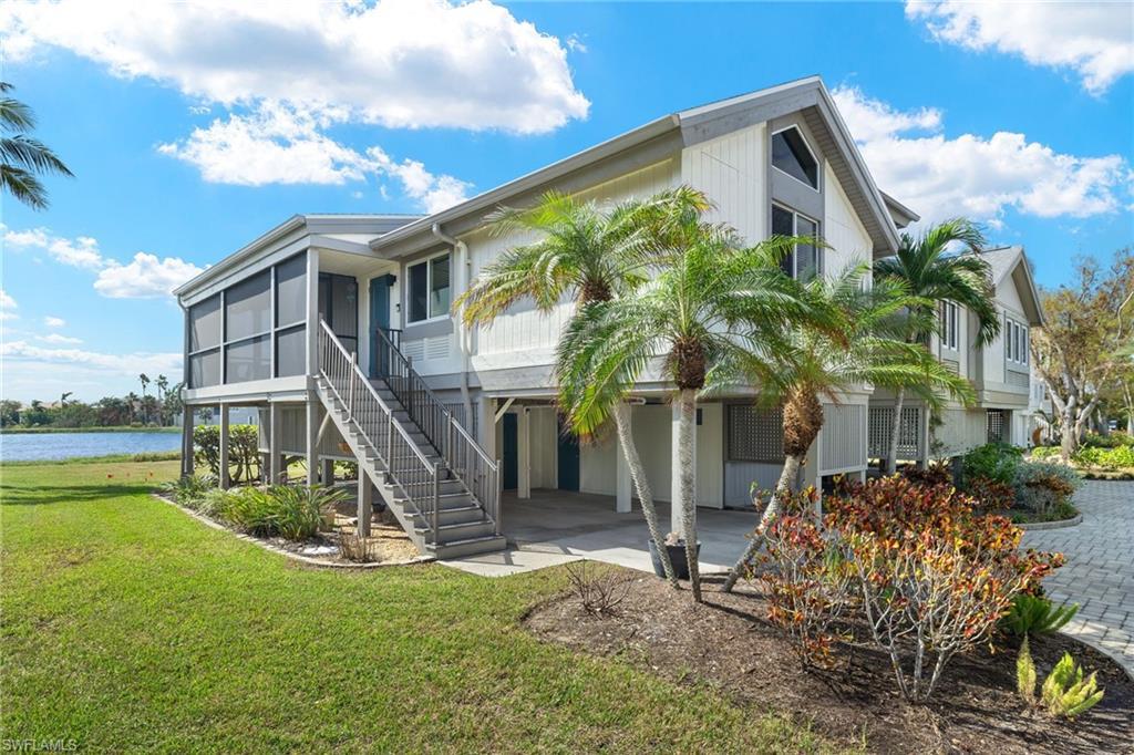 Image 3: Back of property with a water view, a patio, a yard, a sunroom, and stairs