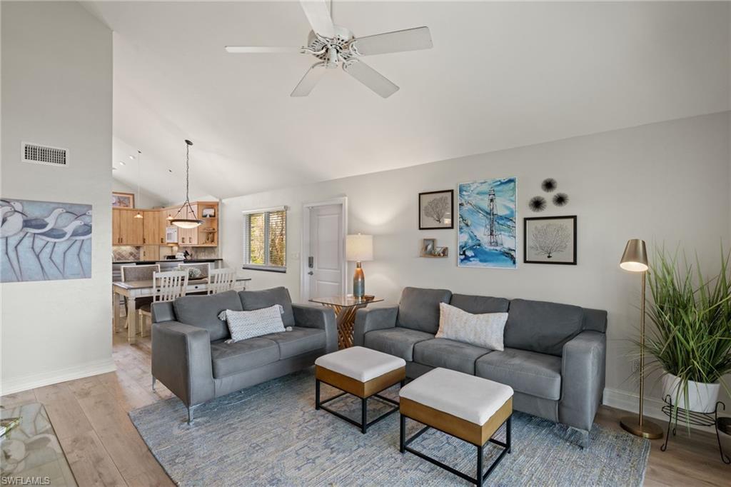 Image 4: Living room with light wood finished floors, ceiling fan, and high vaulted ceiling