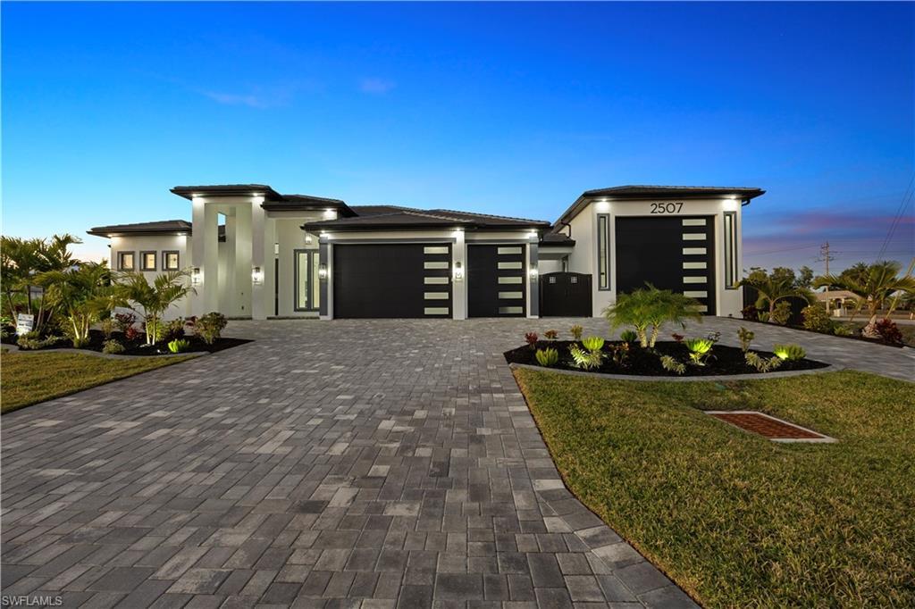 Image 2: Prairie-style house with a garage, a front lawn, decorative driveway, and stucco siding