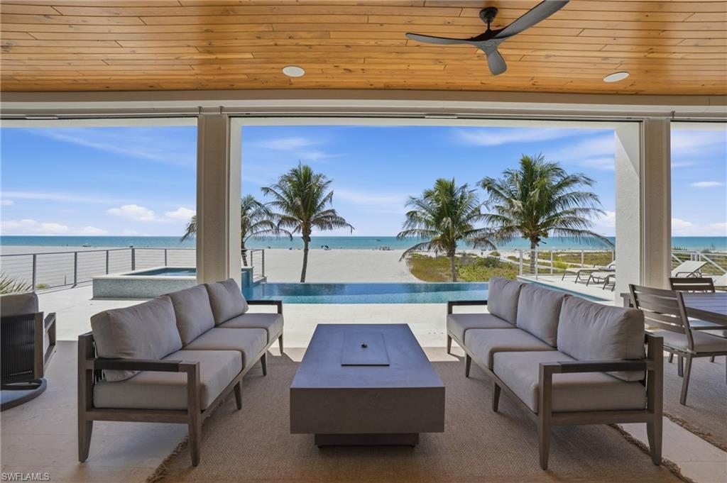 Image 2: View of patio / terrace featuring outdoor lounge area, a ceiling fan, a water view, and an in-ground hot tub - Virtually Edited Image