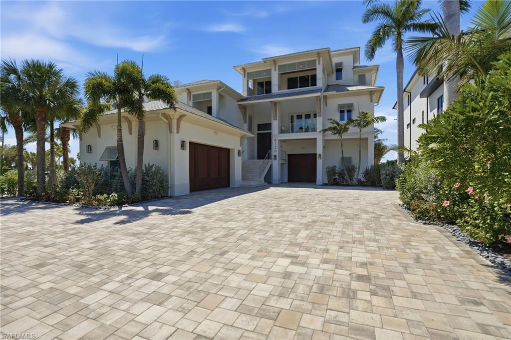 Image 4: Coastal home featuring driveway, stucco siding, and an attached garage - Virtually Edited Image