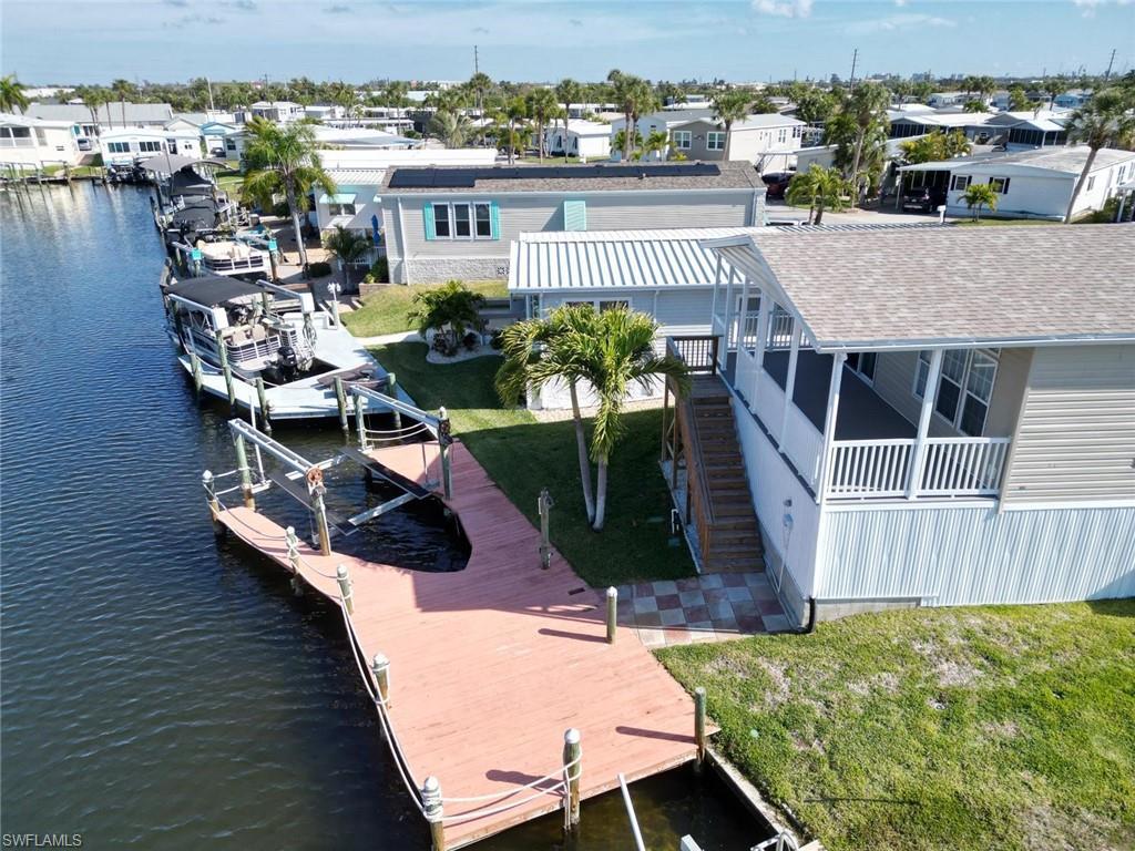 Image 3: Dock area featuring boat lift, a lawn, a residential view, and a water view