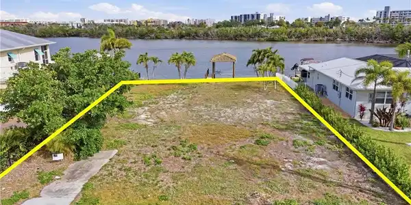 Image 4: View of urban area with property boundaries highlighted and a nearby body of water - Virtually Edited Image