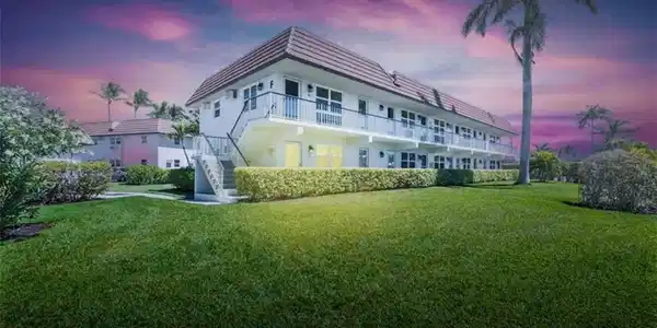 Image 4: Back of property at dusk featuring a lawn, stairway, and stucco sliding.