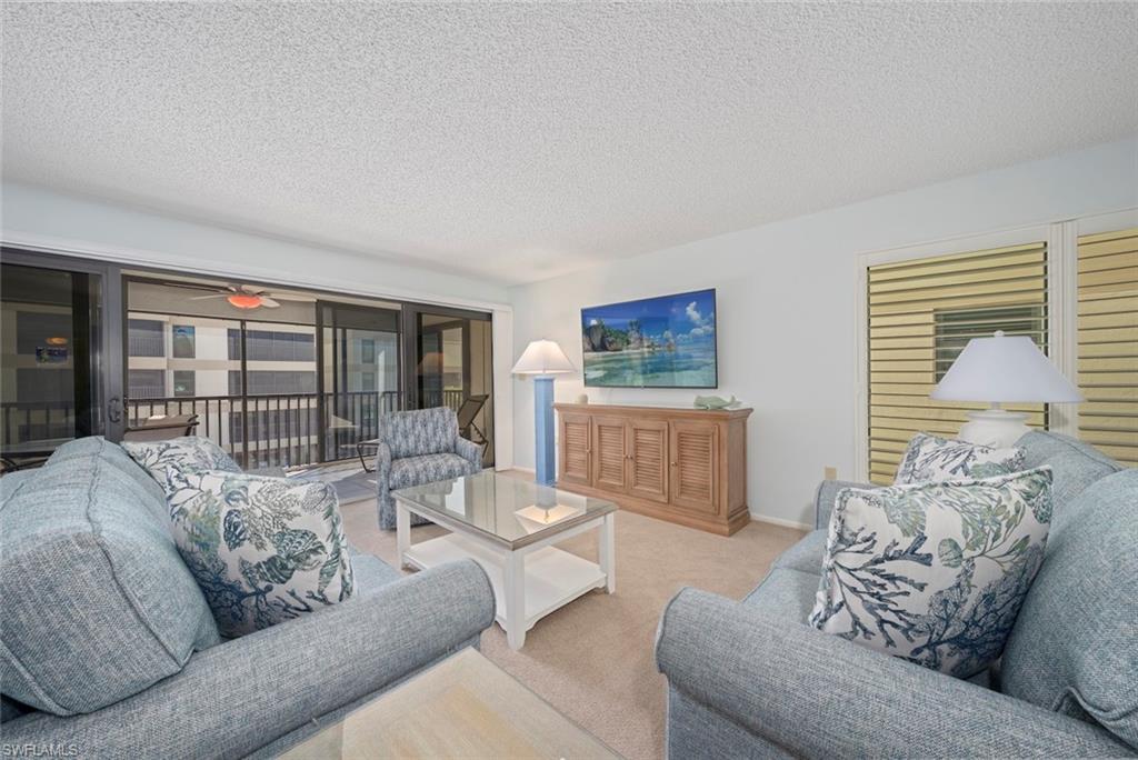 Image 1: Living area with a textured ceiling, carpet, and ceiling fan