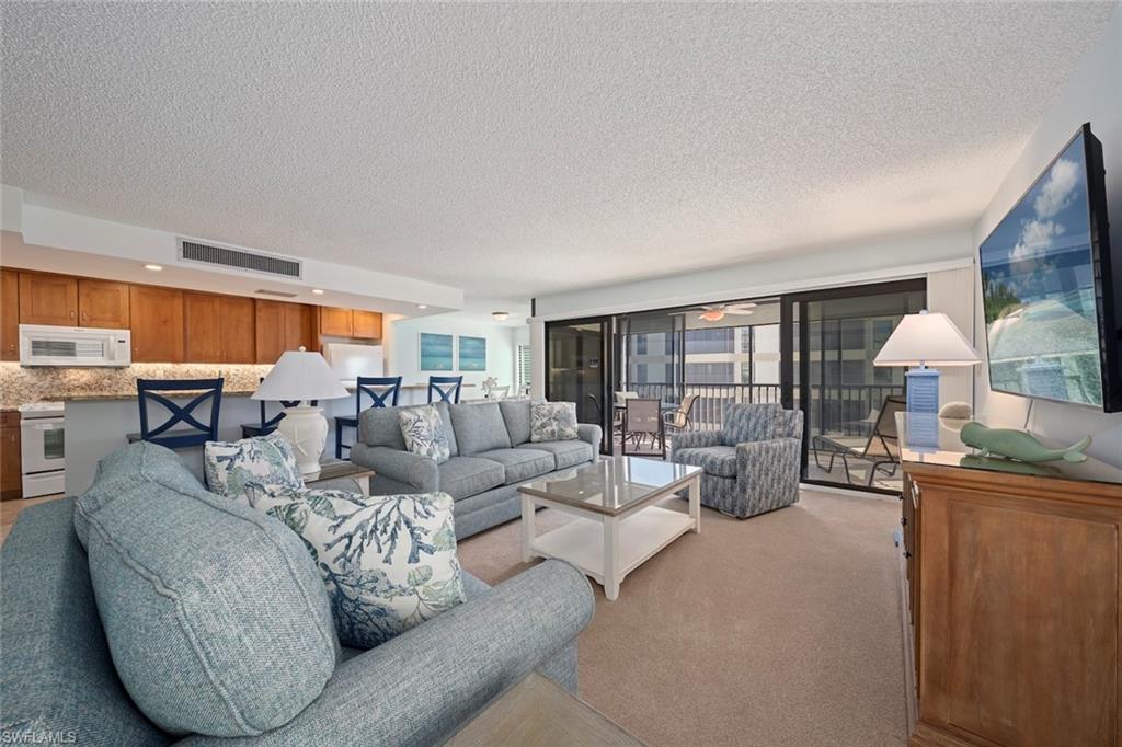 Image 2: Living room with light carpet, a textured ceiling, and a ceiling fan