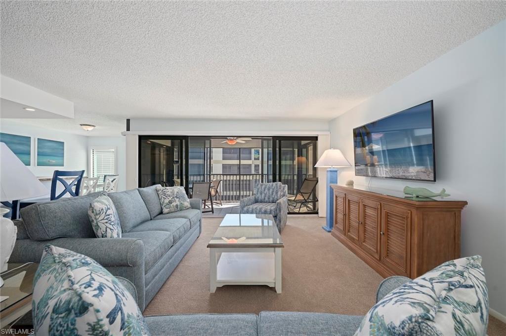 Image 3: Carpeted living area with a textured ceiling