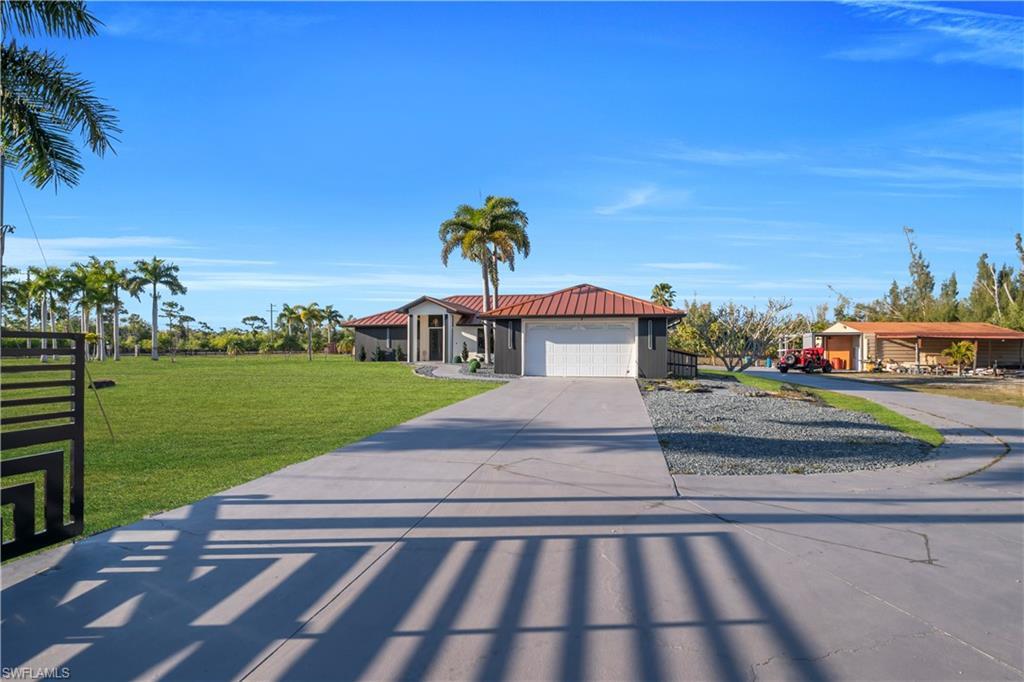 Image 4: View of front of home with concrete driveway, a front lawn, an attached garage, and a metal roof