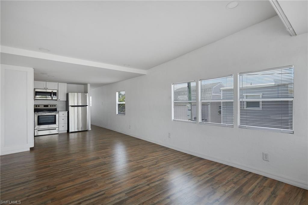 Image 4: Unfurnished living room with baseboards and dark wood-style floors