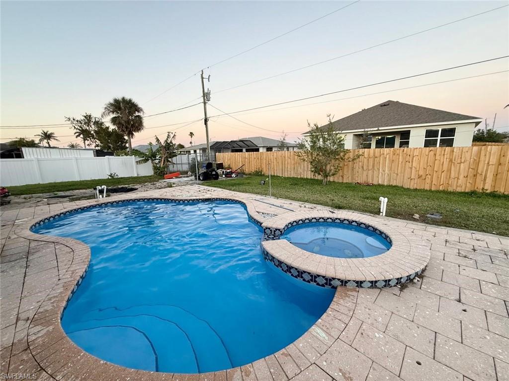 Image 1: Pool at dusk featuring an in ground hot tub and a patio area