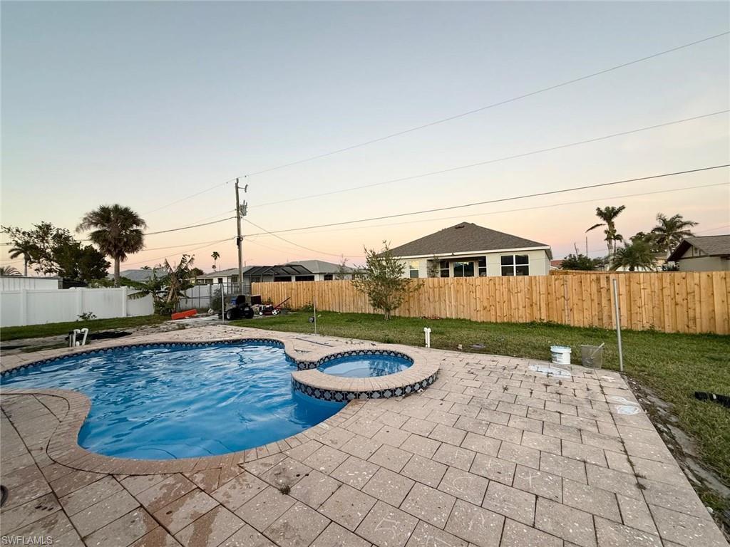 Image 2: Pool at dusk featuring a yard, an in ground hot tub, and a patio area