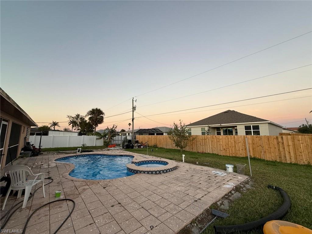 Image 4: Pool at dusk with a patio and an in ground hot tub