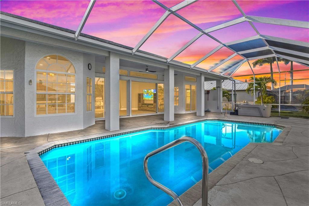 Image 3: Outdoor pool featuring glass enclosure, a sunroom, a patio area, and a hot tub