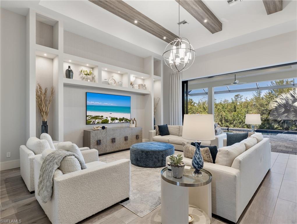 Image 2: Living area with built in features, wood finished floors, recessed lighting, a towering ceiling, and a chandelier