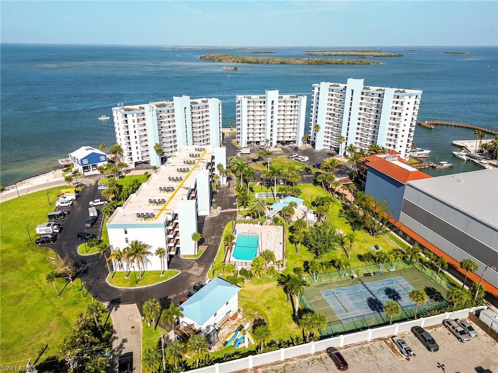 Image 3: Waterfront multi-story buildings featuring balconies, a swimming pool, tennis court, and marina access
