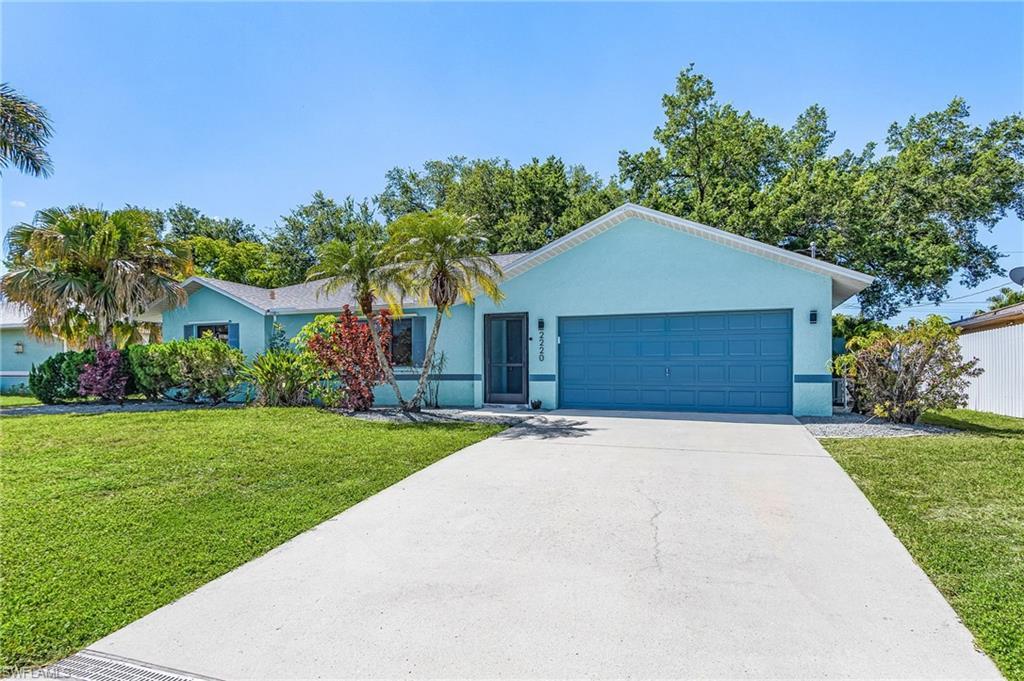 Image 3: Single-story residence featuring a two-car garage, concrete driveway, and a vibrant blue exterior