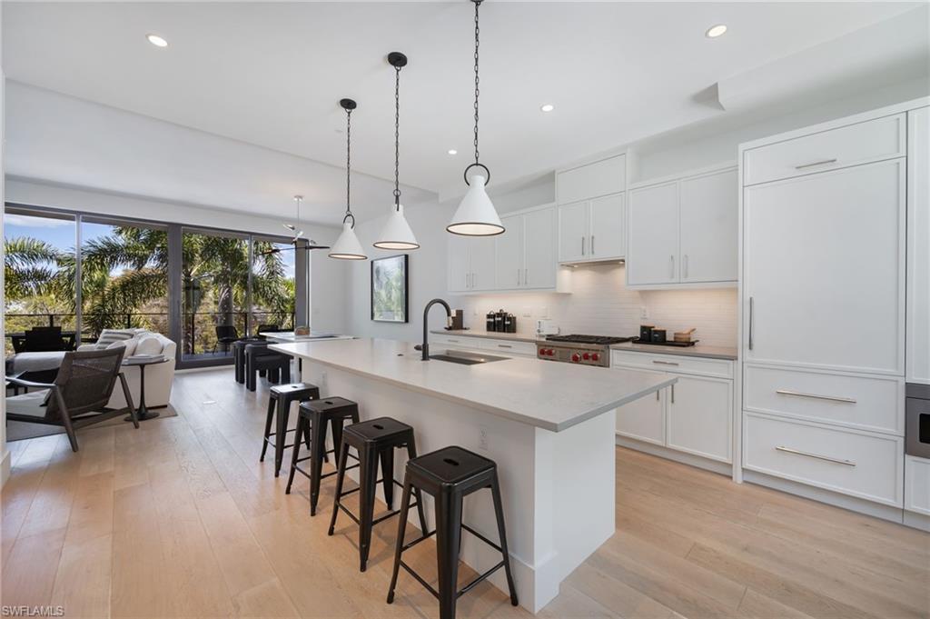 Image 1: Kitchen with white cabinets, a breakfast bar, and an island with sink