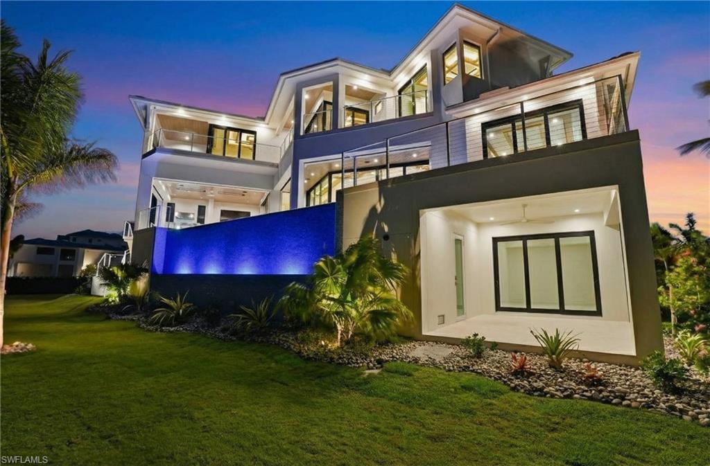 Image 4: Rear view of house with stucco siding, a balcony, and a lawn - Virtually Edited Image