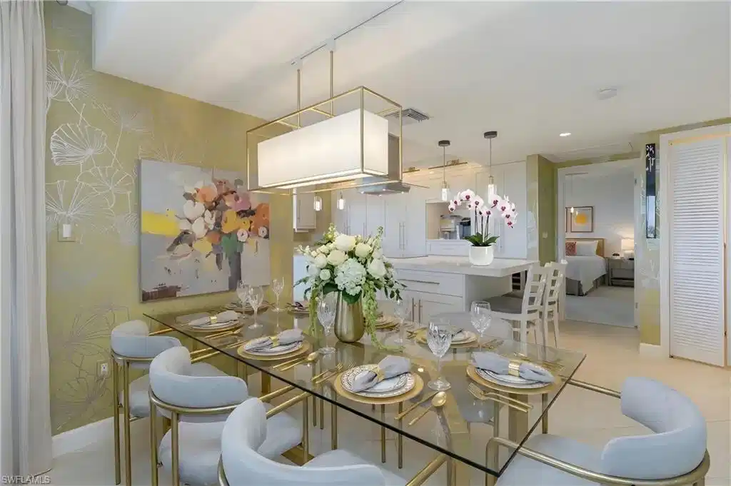 Image 1: Open-concept dining area with a glass-top table, gold-finished chairs, and a rectangular pendant light fixture