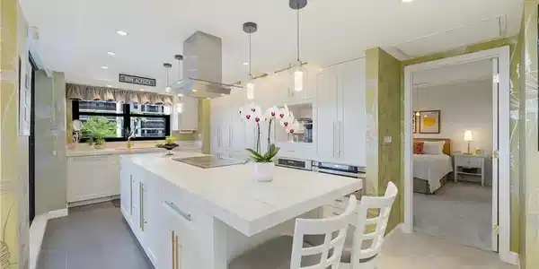Image 3: Contemporary kitchen featuring a large center island with integrated cooktop, white cabinetry, and stainless steel appliances