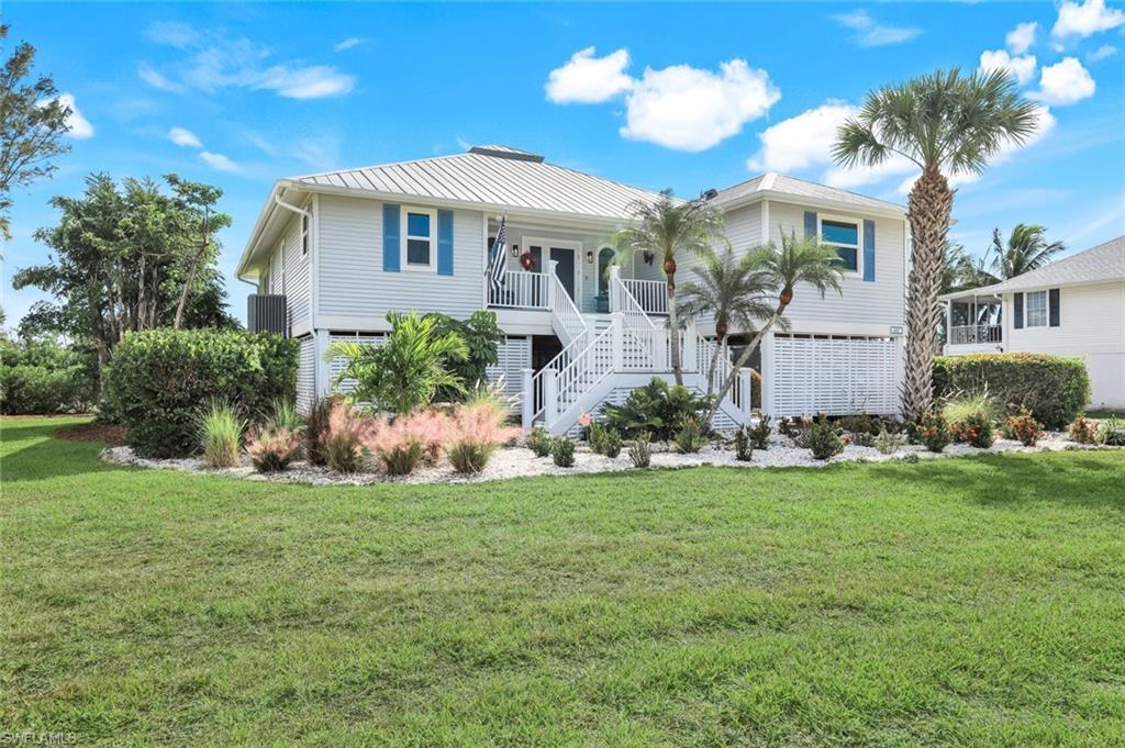 Image 2: Beach home with stairway, a front yard, and a metal roof