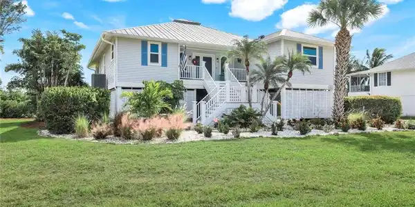 Image 2: Beach home with stairway, a front yard, and a metal roof