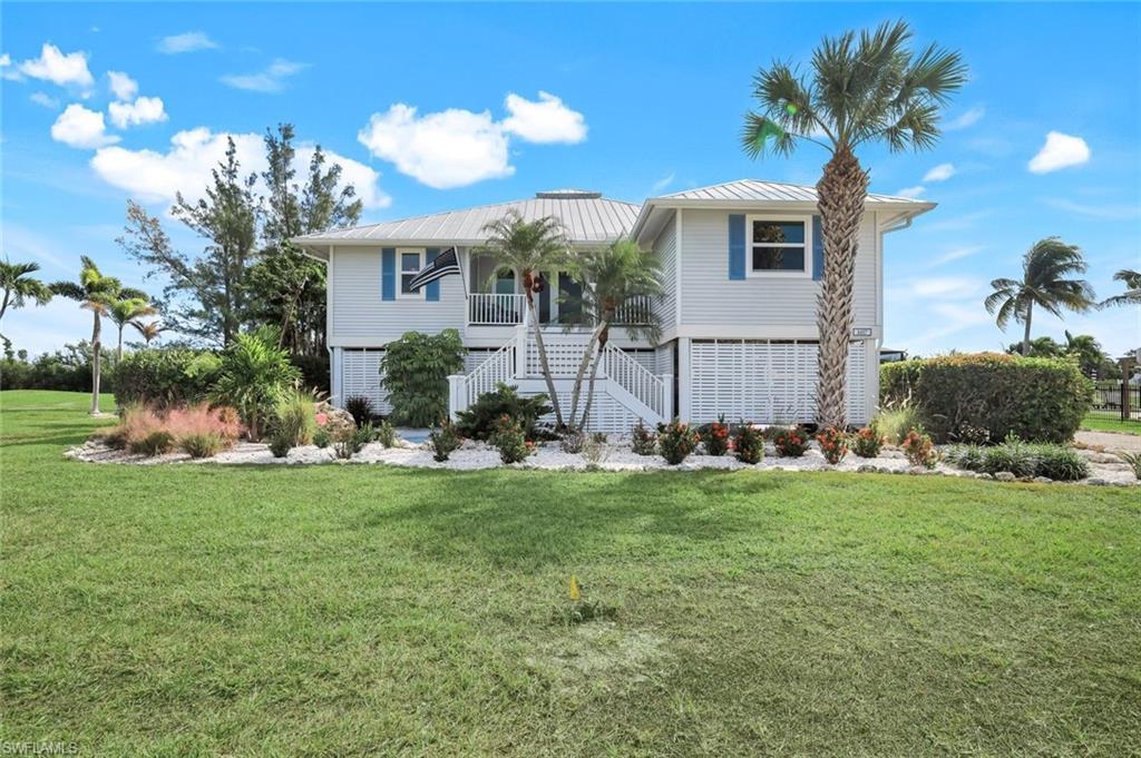 Image 3: Raised beach house featuring a front yard, stairs, a metal roof, and a standing seam roof