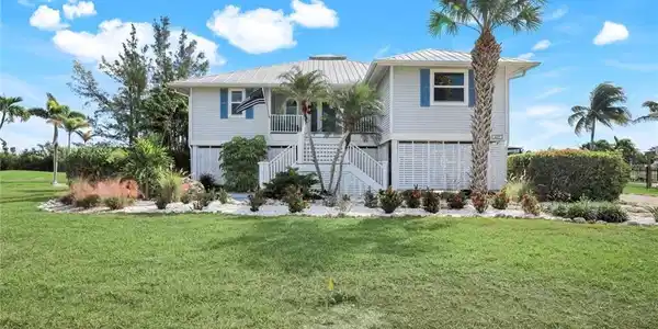 Image 3: Raised beach house featuring a front yard, stairs, a metal roof, and a standing seam roof