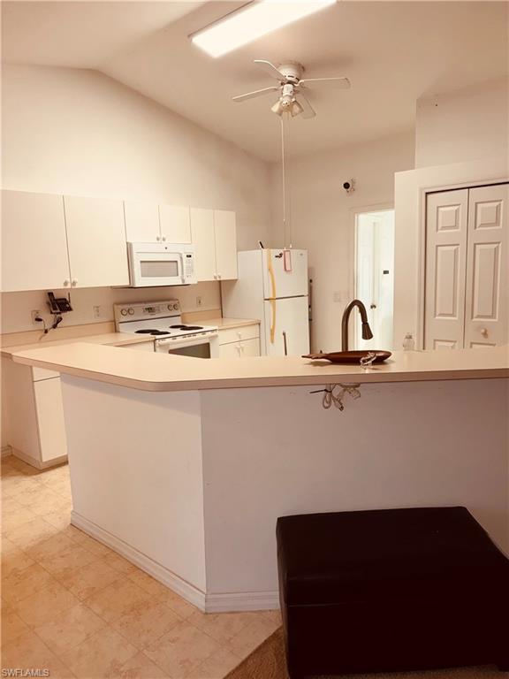 Image 2: Kitchen with a peninsula, light countertops, white appliances, white cabinets, and ceiling fan