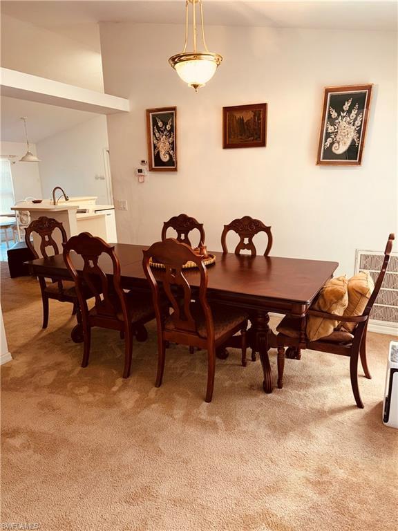 Image 4: Dining room featuring light colored carpet and vaulted ceiling