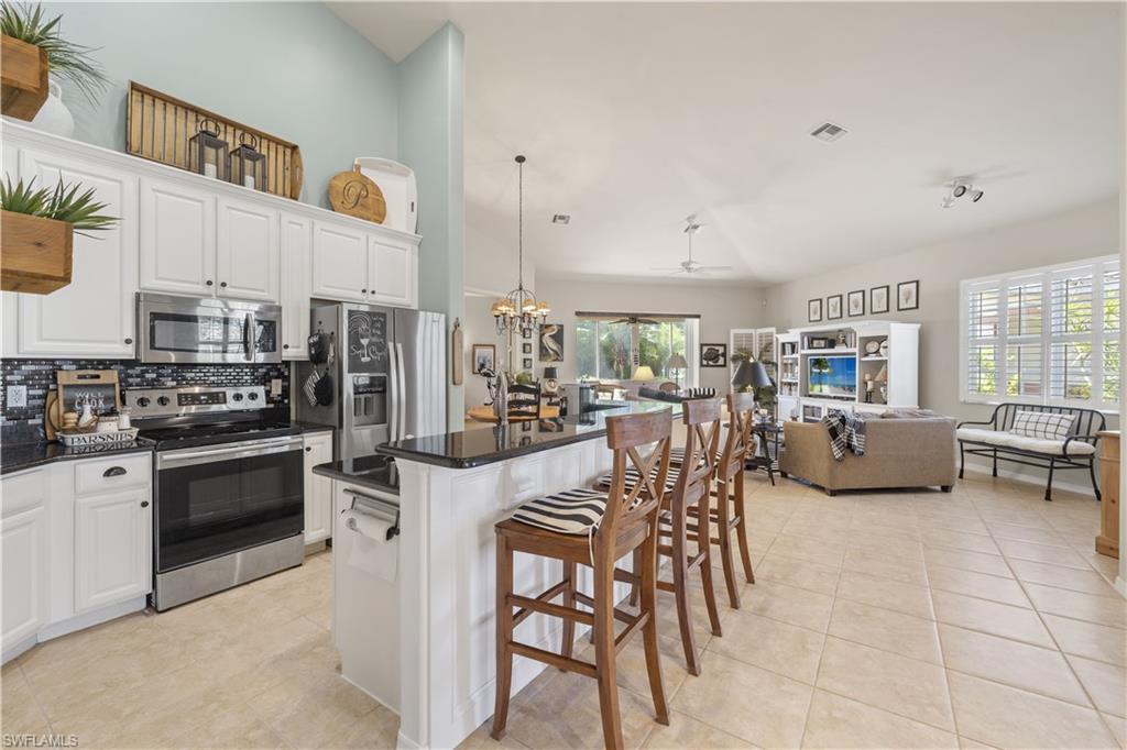 Image 3: Kitchen featuring a wealth of natural light, stainless steel appliances, a kitchen island, a breakfast bar, and white cabinets
