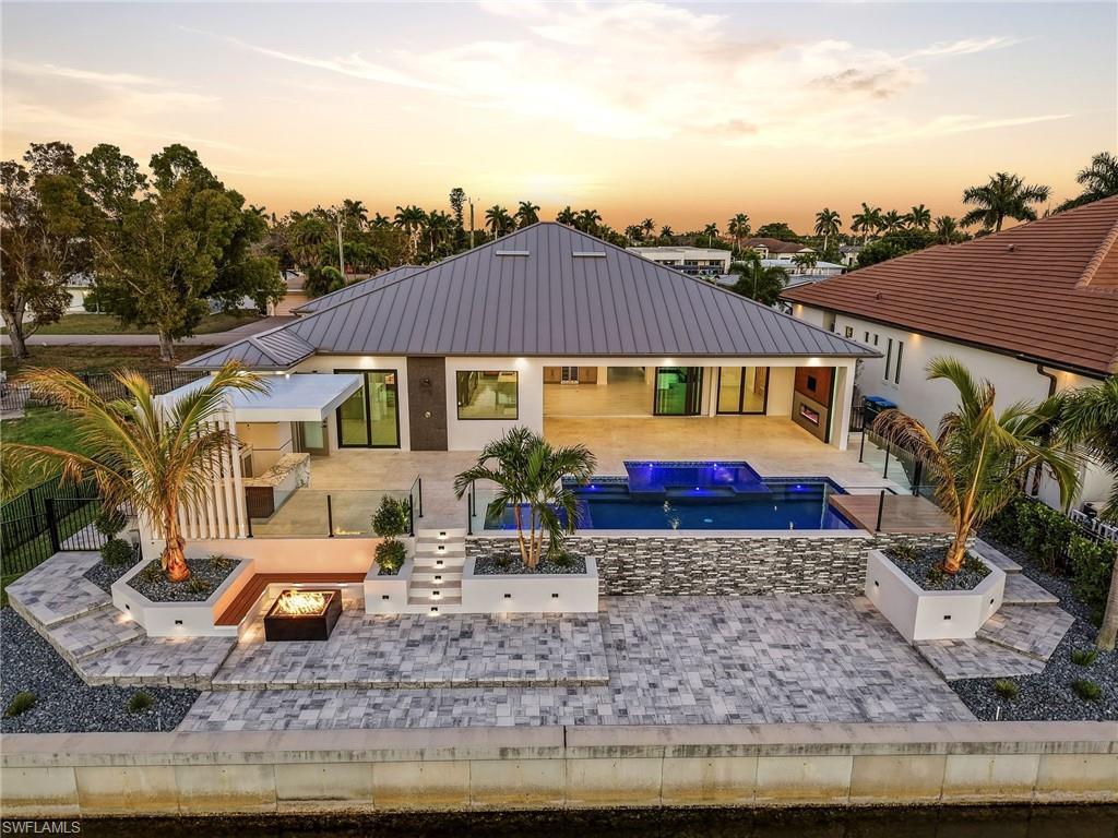 Image 2: Back of house with a patio area, a jacuzzi, a fenced backyard, an outdoor pool, and a fire pit