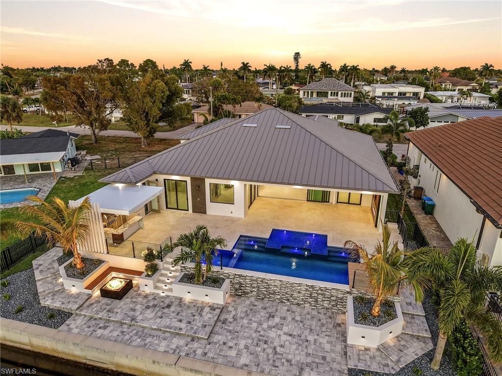 Image 3: Back of house at dusk featuring a fenced backyard, an outdoor pool, a patio, and an outdoor fire pit