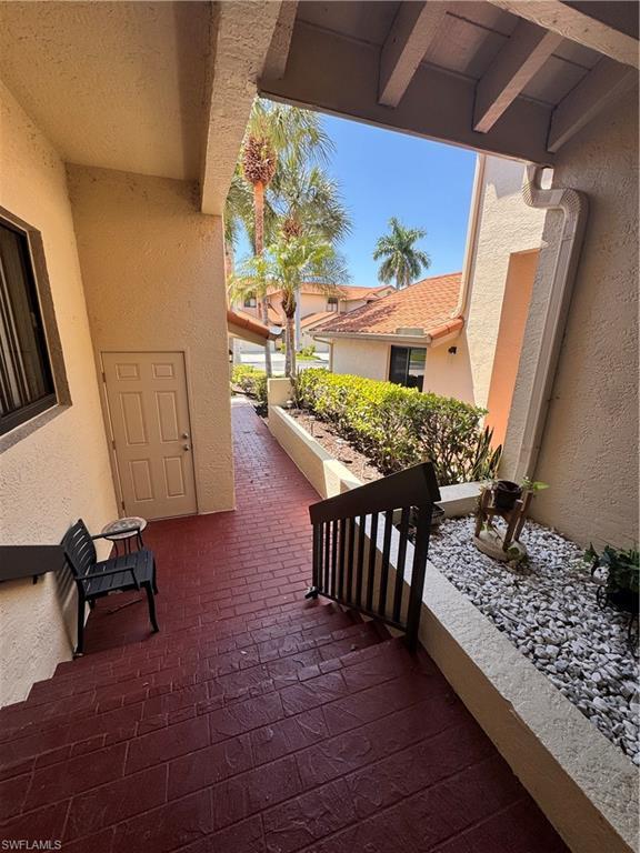 Image 3: Entryway featuring stamped brick-patterned flooring, a black metal handrail, stucco exterior walls, and a landscaped rock garden