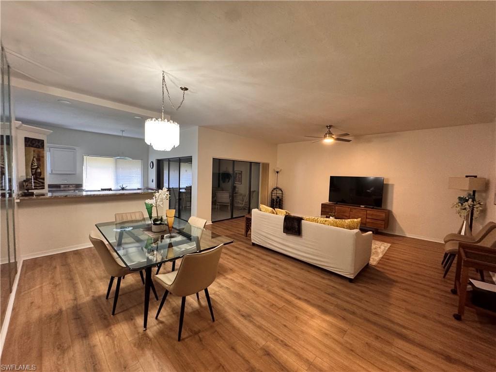 Image 4: Open-concept living area featuring wood-finish flooring, a contemporary dining chandelier, and a breakfast bar with a stone-look countertop