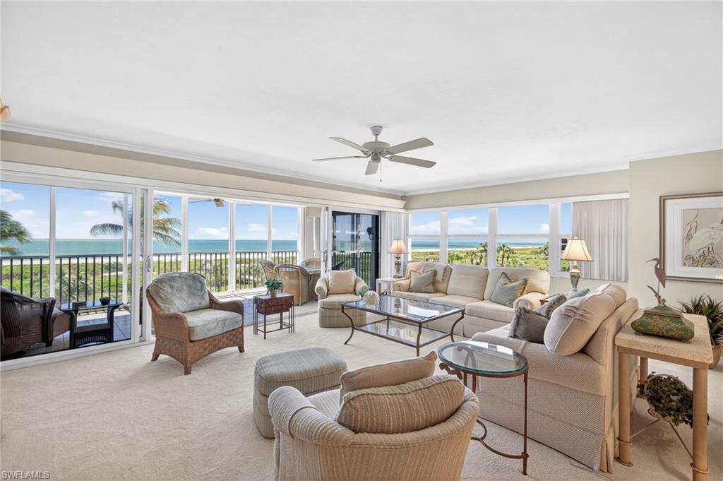 Image 4: Living area featuring expansive windows with ocean views, light-colored carpeting, and a ceiling fan