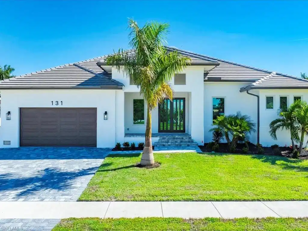 Image 1: View of front of house featuring a front lawn, decorative driveway, a tiled roof, and a garage
